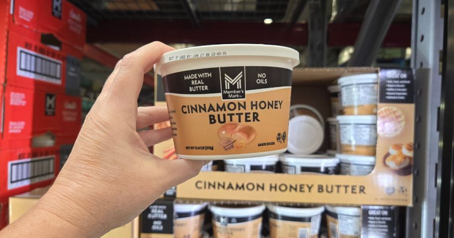 A person holding a Member's Mark Cinnamon Honey Butter tub in front of a fridge full of the same