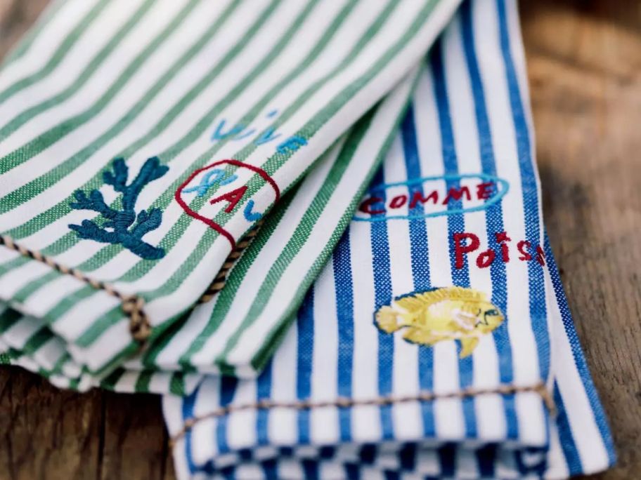 two striped napkins in green and blue with sweet sayings on it 