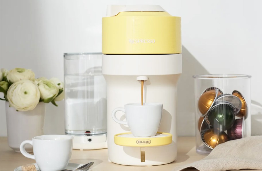 yellow and white nespresso machine brewing a cup of coffee in kitchen