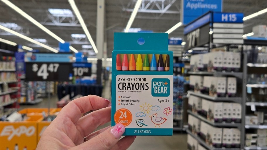 a womans hand holding a box of crayons