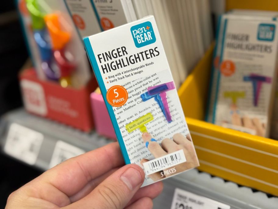 A person holding a white box containing finger highlighters in a store
