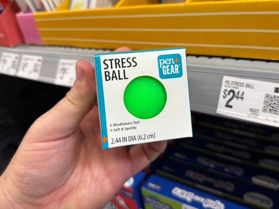 A person holding a white box with a green stress ball inside