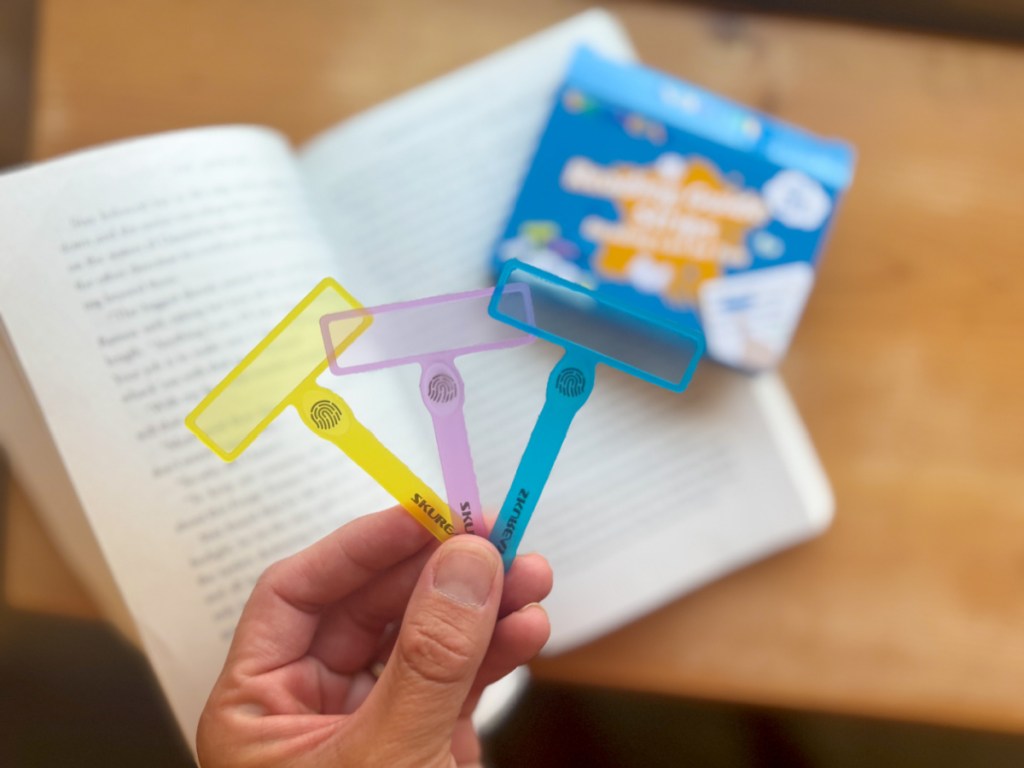 Person holding up color Guided Reading Strips above paperback book