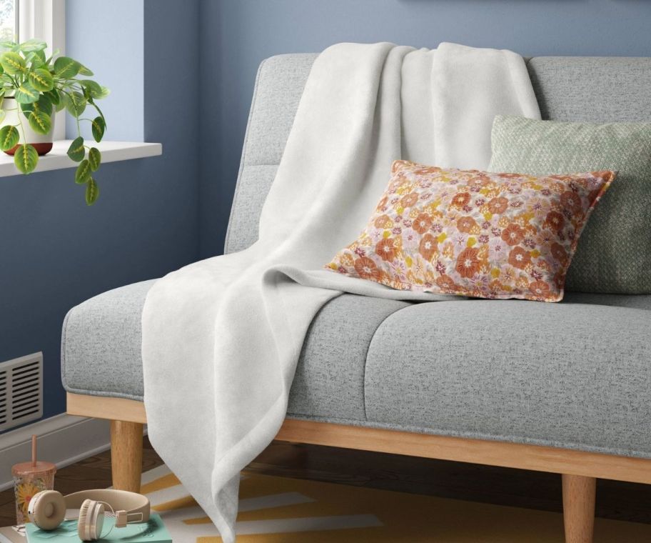 an ivory colored throw blanket draped across a sofa