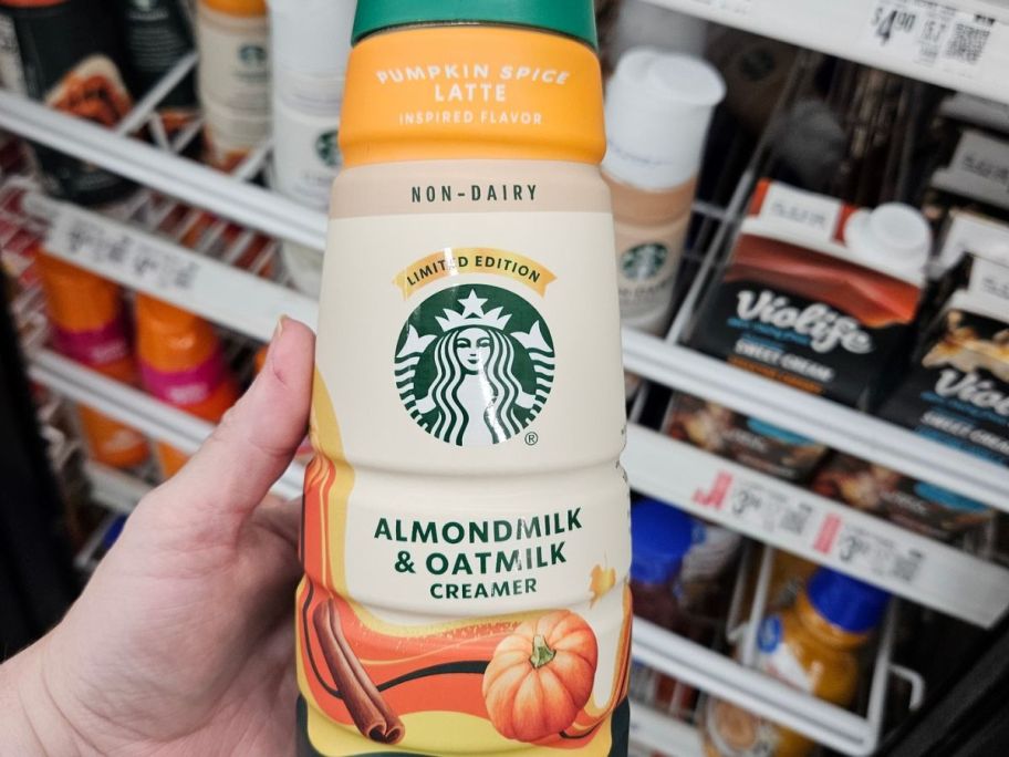 Hand holding a bottle of Starbucks Pumpkin Spice Latte Non-Dairy Creamer