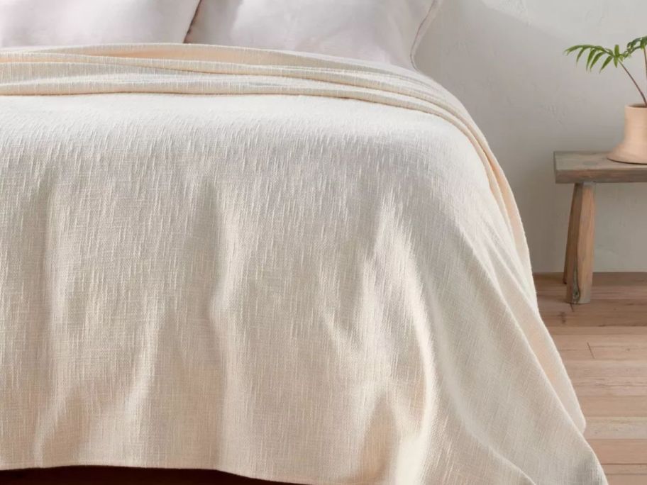 beige blanket displayed on top of a bed