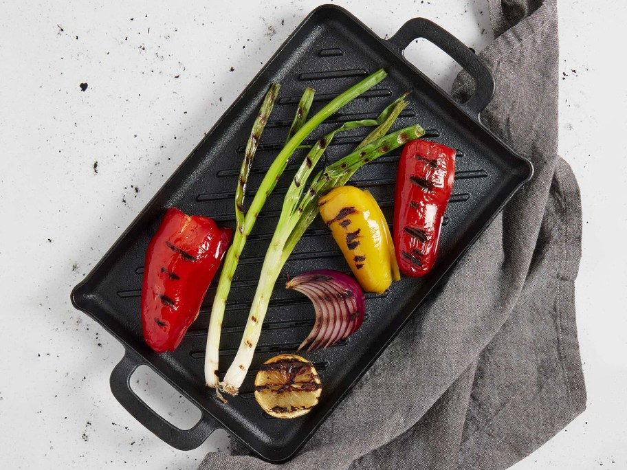 The Big One Pre-Seasoned Cast-Iron Grill on a counter with food