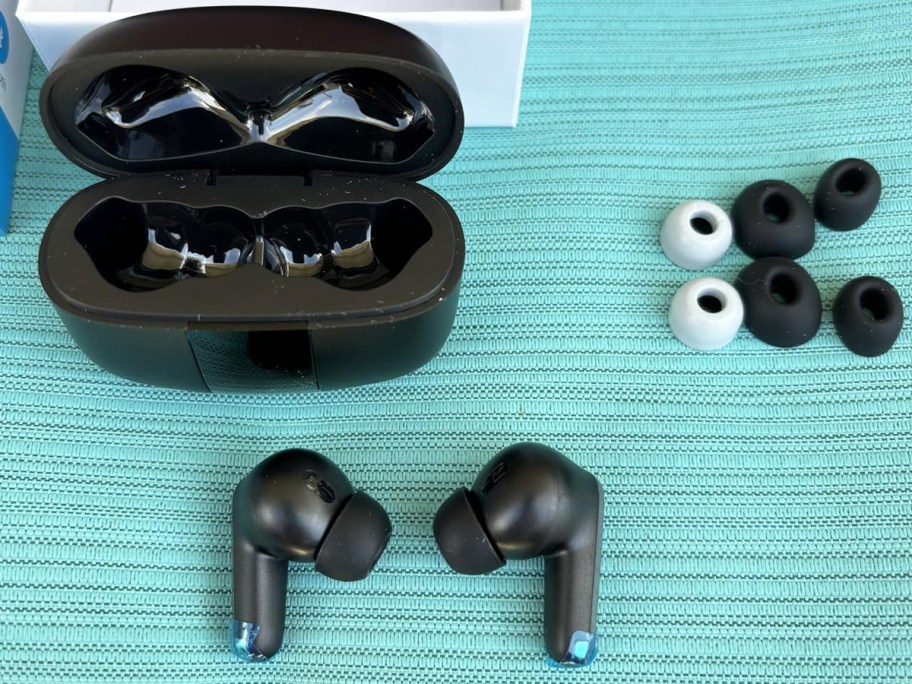 black ear buds, charging case, and ear tips laid out on table