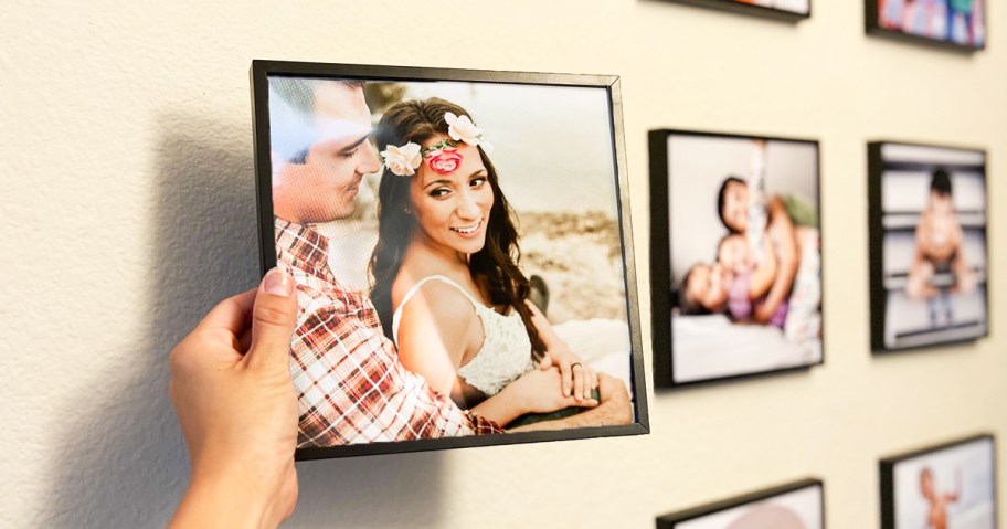 hand holding a photo of a couple on a gallery wall