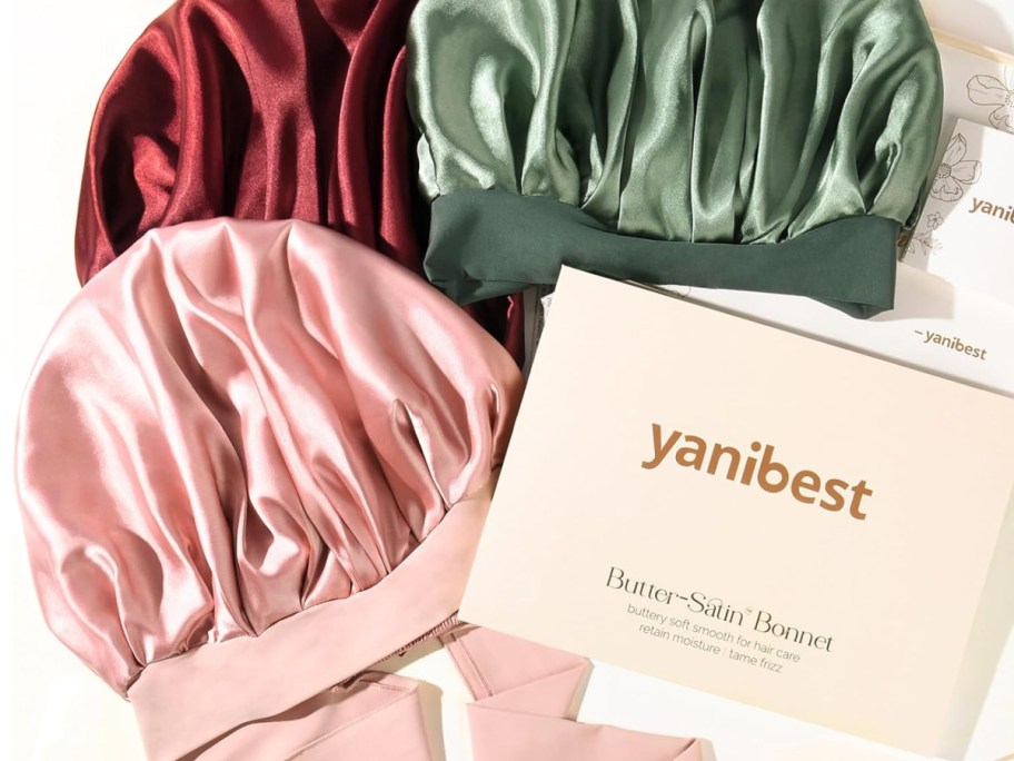 Different colored Yanibest satin bonnet next to white gift box
