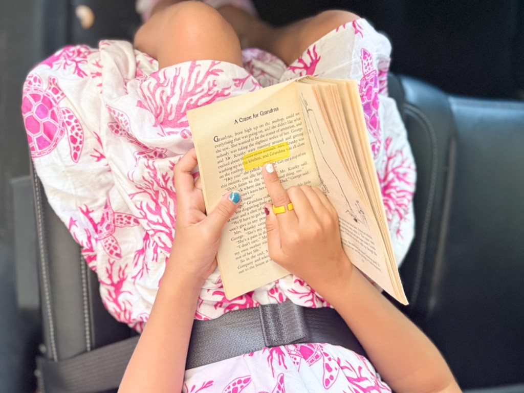 Little girl, reading book using yellow plastic guide strip