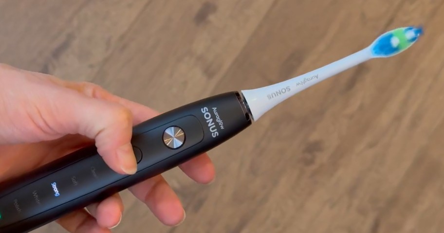 hand holding aura glow toothbrush 