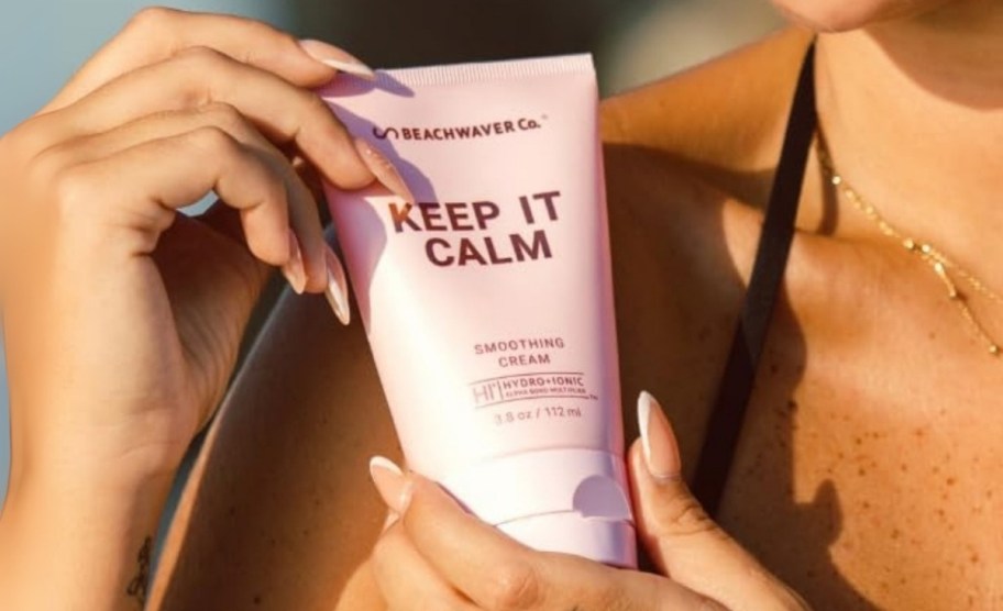 a womans hand holding a tube of hair cream