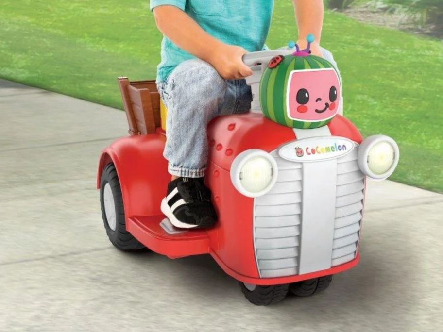boy riding on Cocomelon Ride-On Tractor on sidewalk