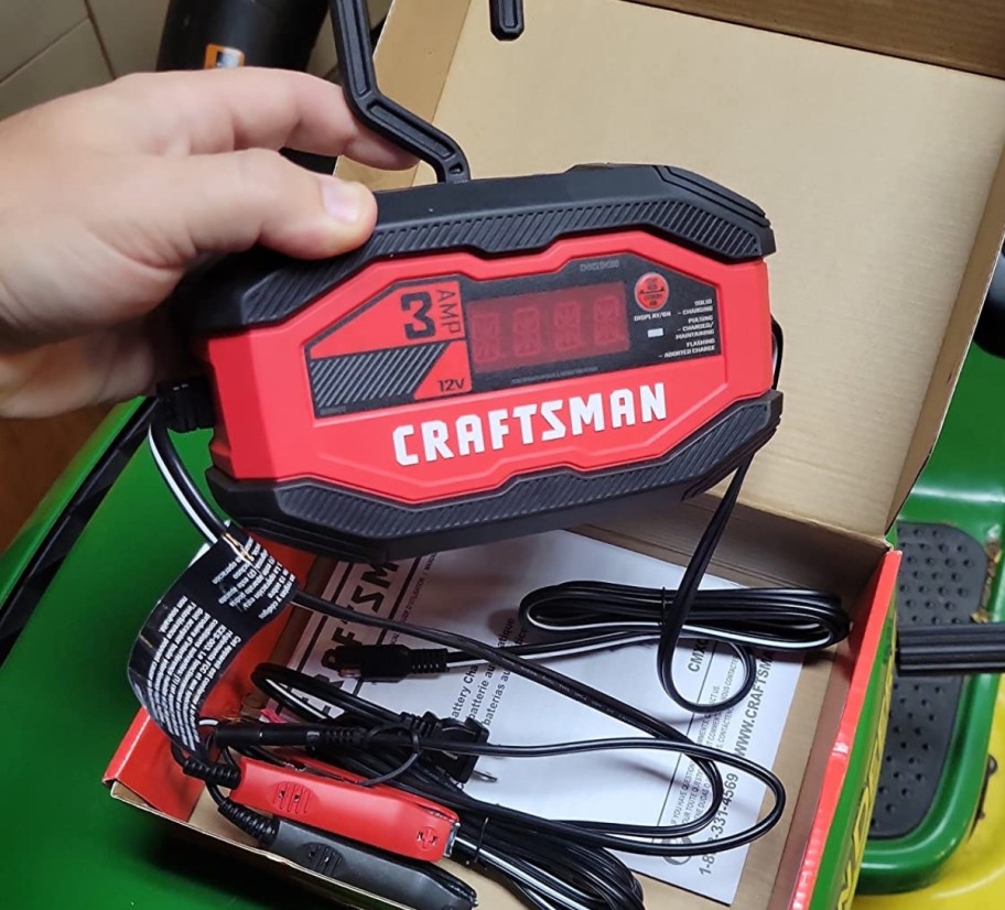 a mans hand holding a car battery charger