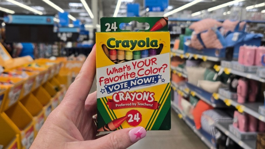 a womans hand holding a box of crayons