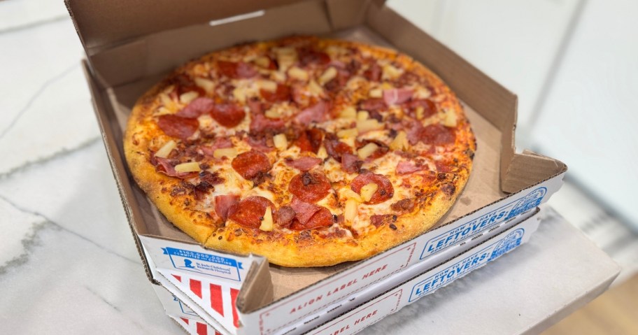 two Domino's pizza boxes on a counter, the top is open showing a pizza
