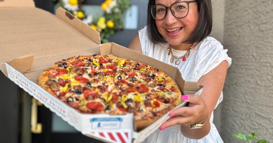 woman holding a Domino's pizza box with a pizza in it