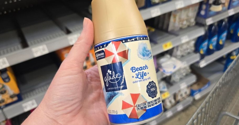 a womans hand holding a can of automatic mist spray refill