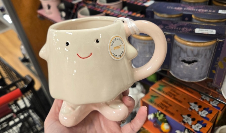 a womans hand holding a ceramic ghost mug