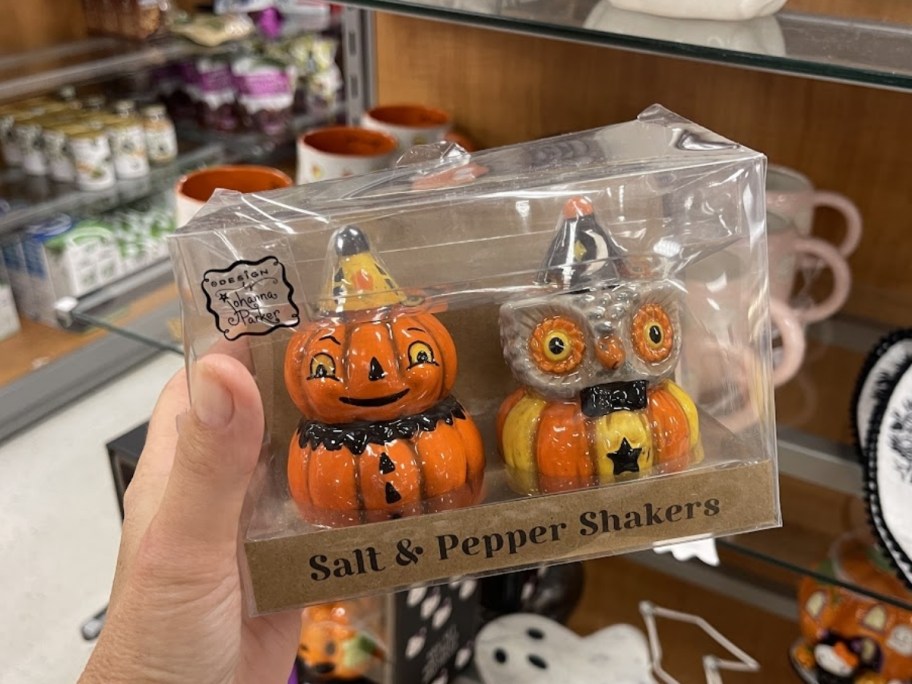 a womans hand holding a set of salt and pepper shakers