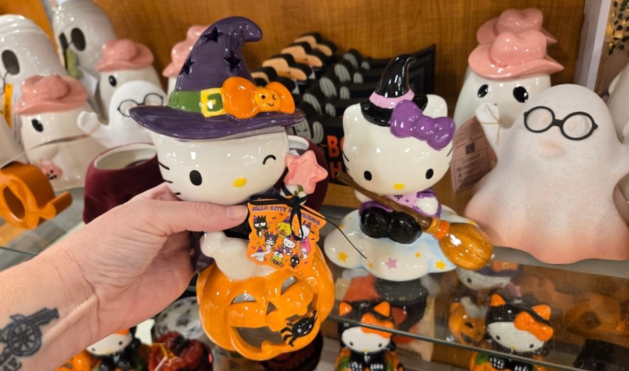 womans hand holding a hello kitty halloween figurine
