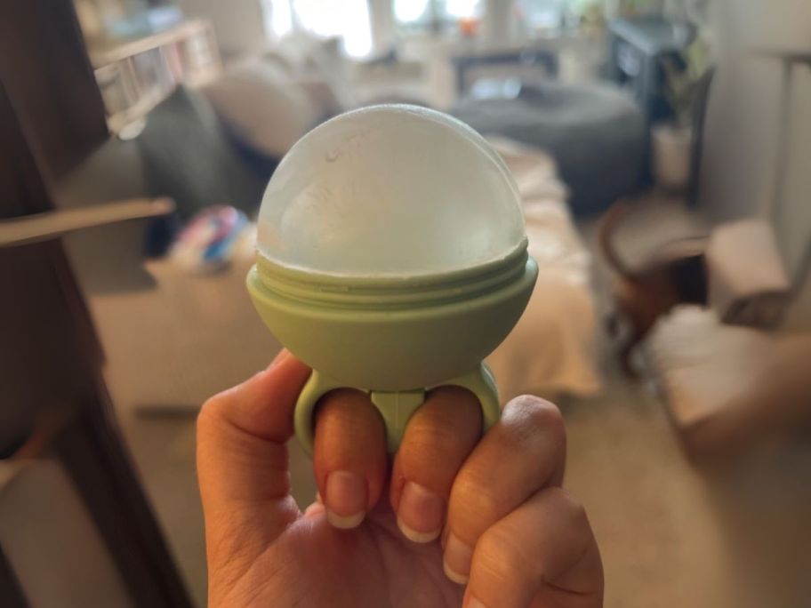 green facial ice roller in hand