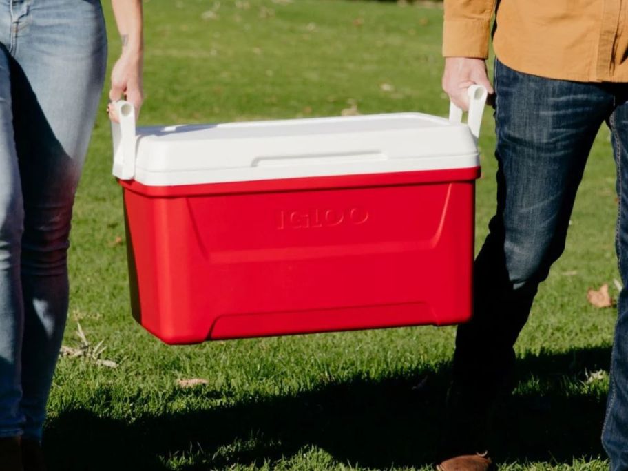 two people carrying red igloo cooler