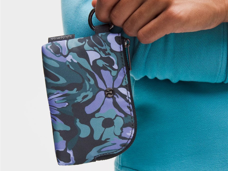 person holding a blue and teal floral print card pouch