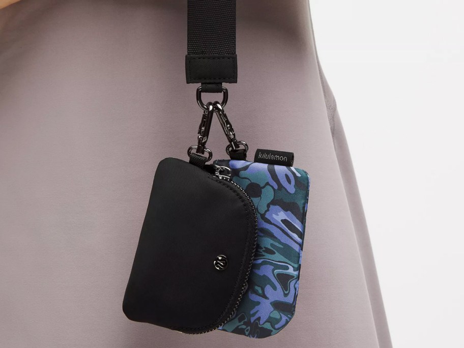 person holding a black and blue floral print dual pouch wristlet