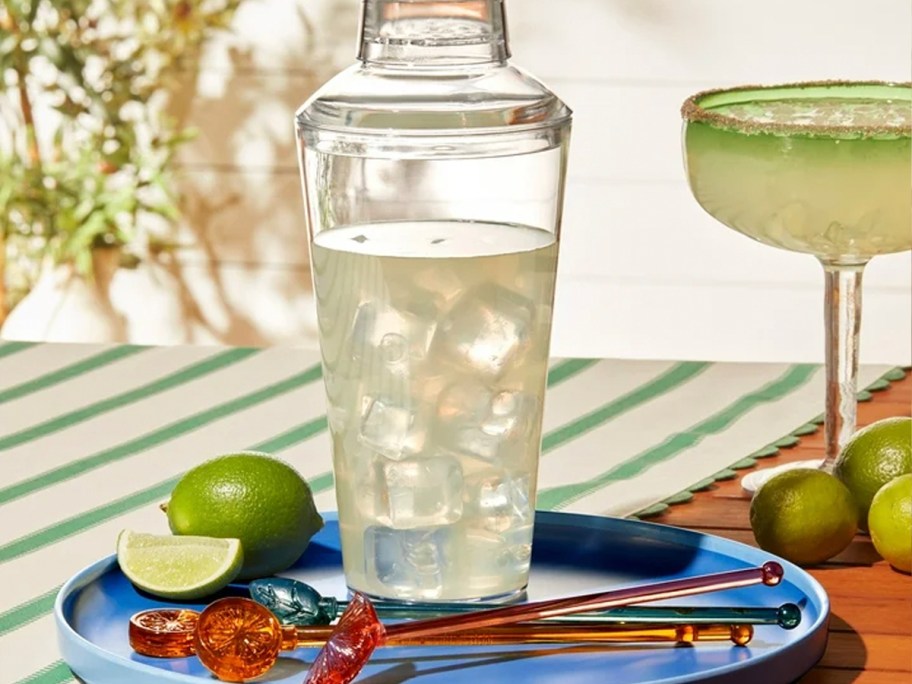 clear cocktail shaker with sticks on blue plate 
