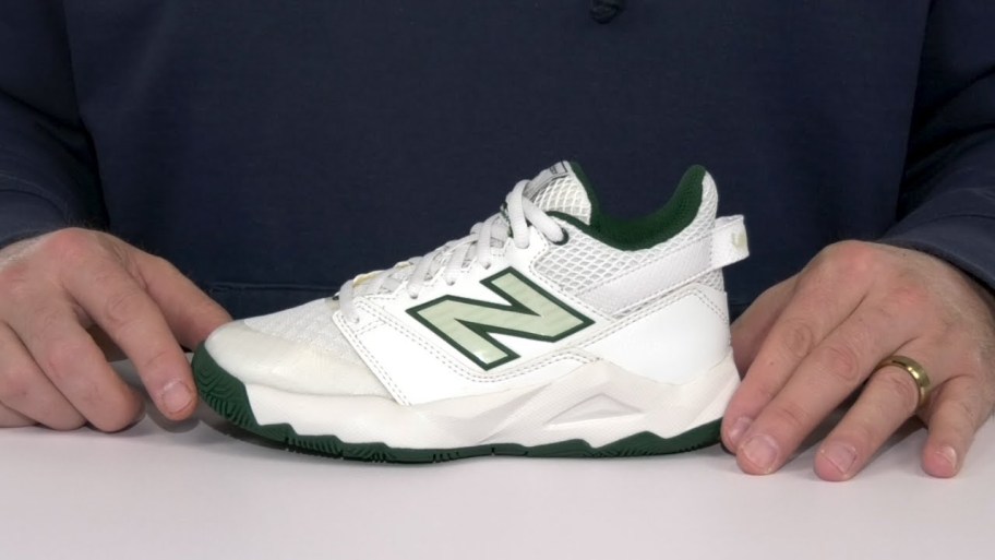 hands holding green and white new balance shoe