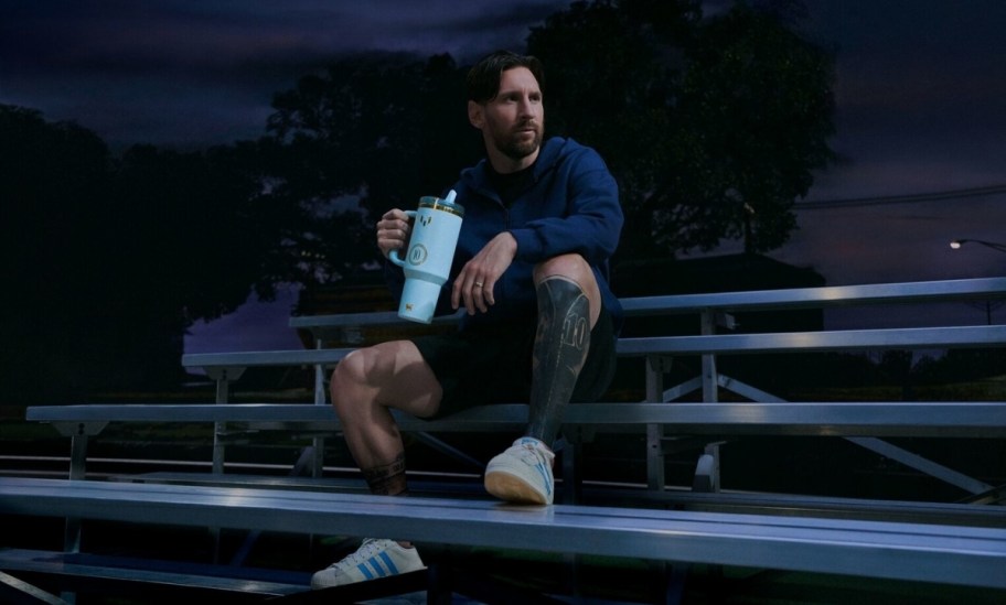 a man sitting on bleachers and holding a 40oz drink tumbler