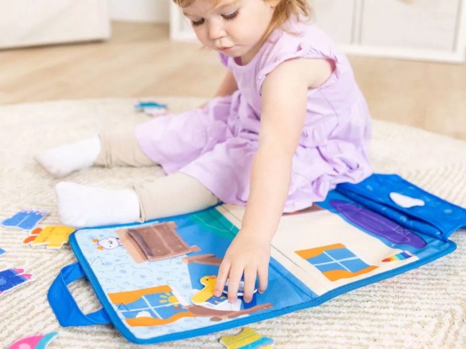 girl playing with a dress up play book on the floor