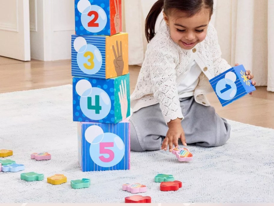 girl playing with learning blocks on the floor
