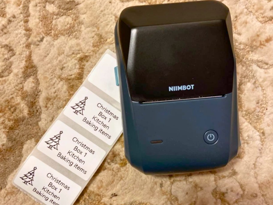 a wireless label maker with a sheet of printed labels beside it
