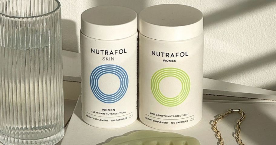 two nutrafol supplement bottles next to glass of water