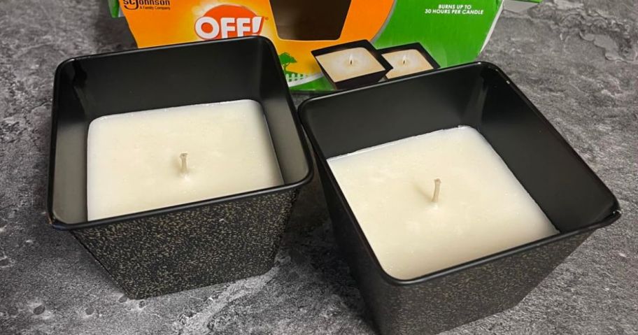two off citronella candles on table in front of box