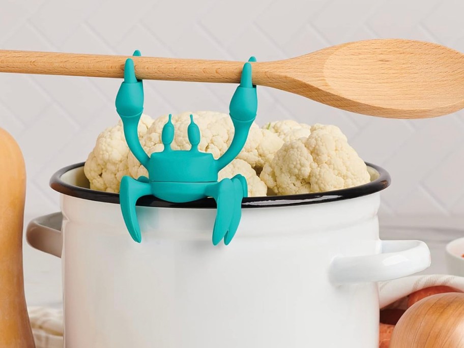 blue crab spoon holder holding spoon over pot 