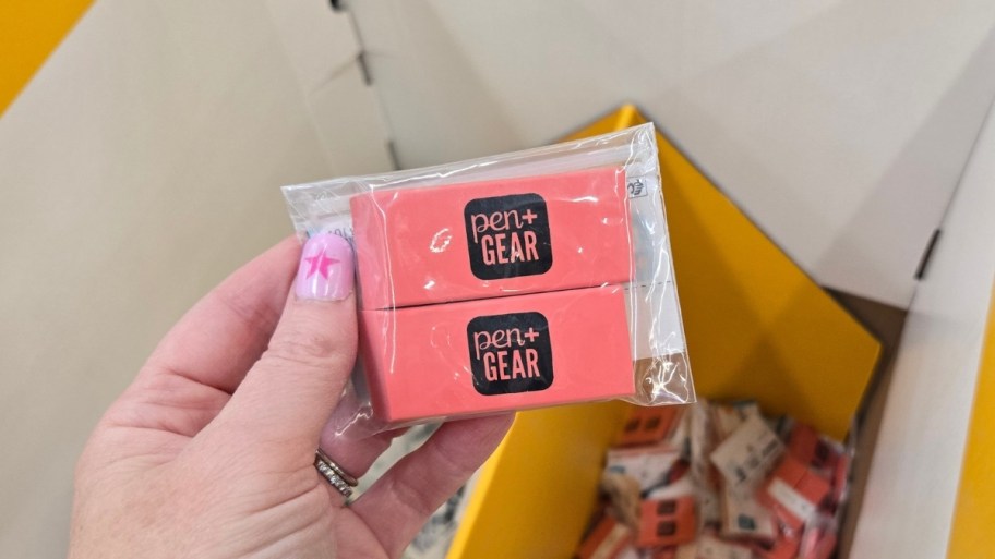 a womans hand holding a 2 pack erasers