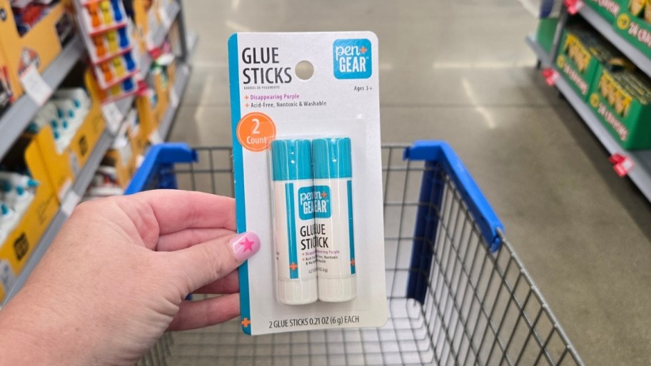 a womans hand holding a 2 pack of glue sticks