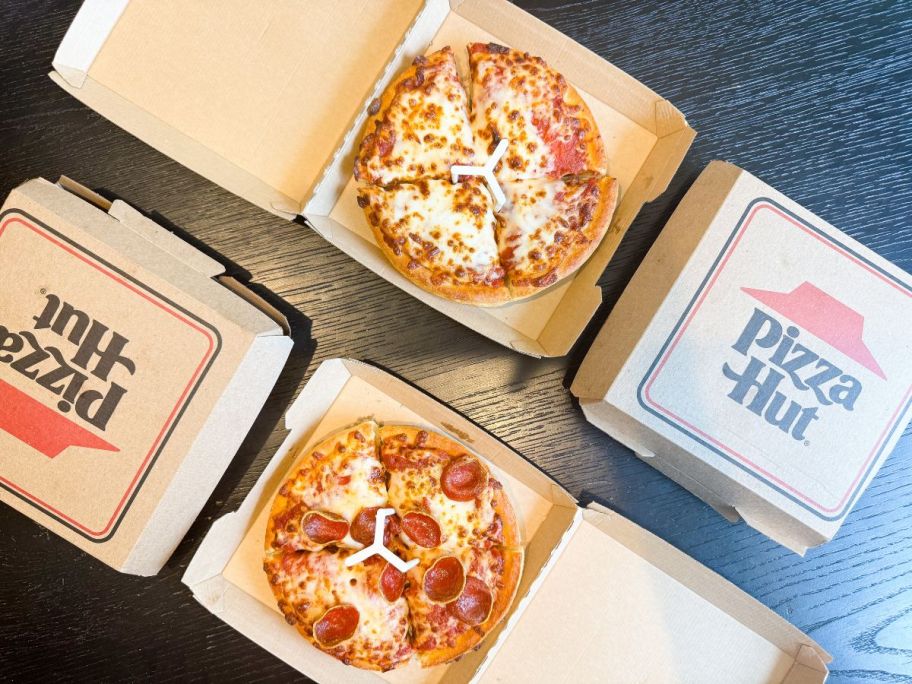 Pizza Hut personal pizzas in their boxes on a table