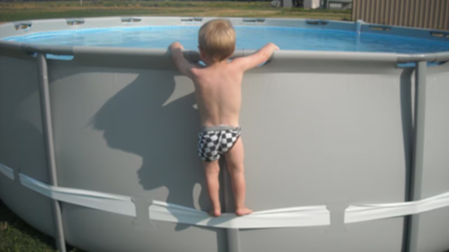 baby climbing on exterior of above ground pool