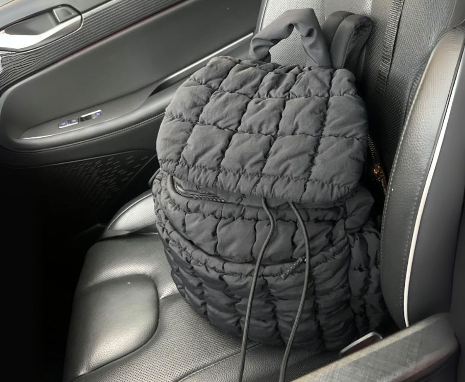  a black puffer backpack on a front passenger car seat