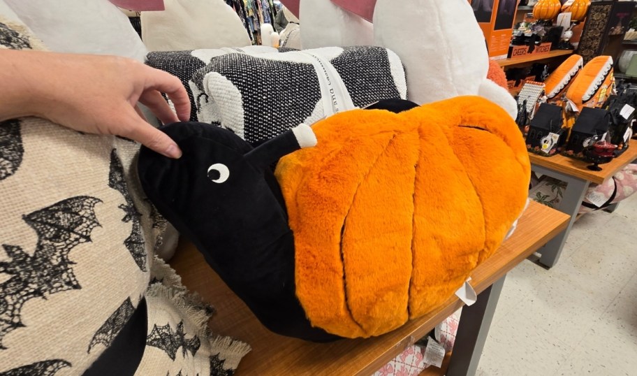 a womans hand holding a pumpkin turtle plush