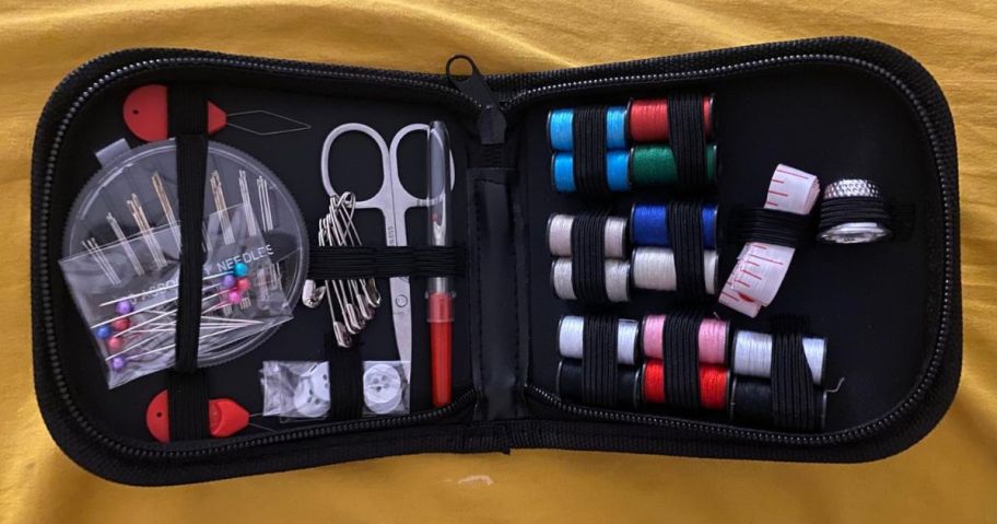 sewing kit open with sewing accessories inside on table
