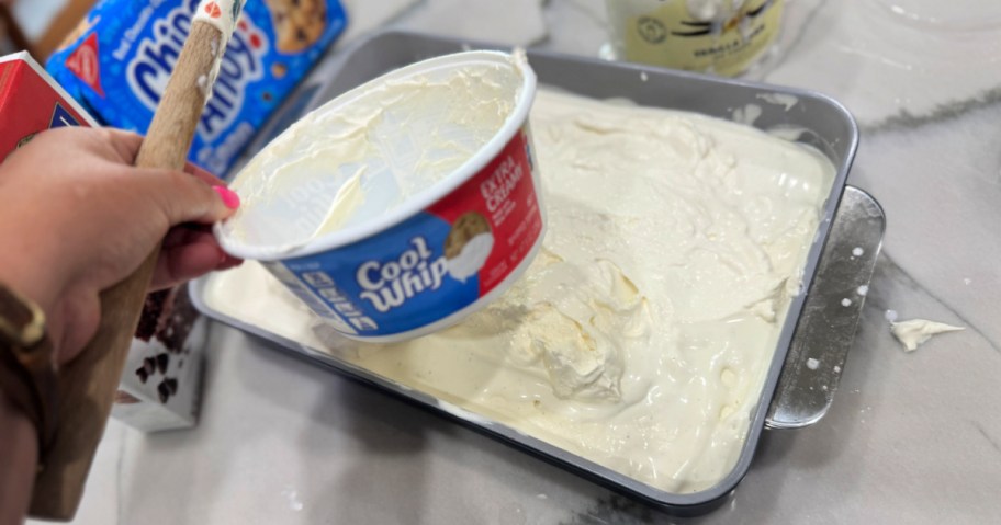 spreading whipped topping onto an ice cream cake 