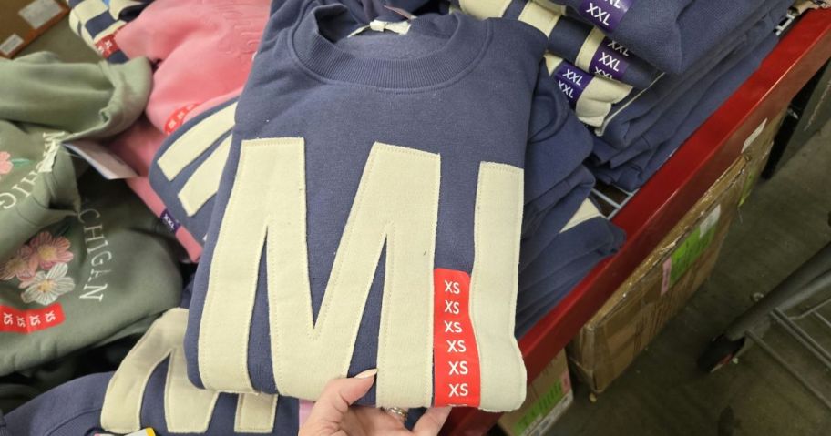 hand holding blue sweatshirt with MI on it in store