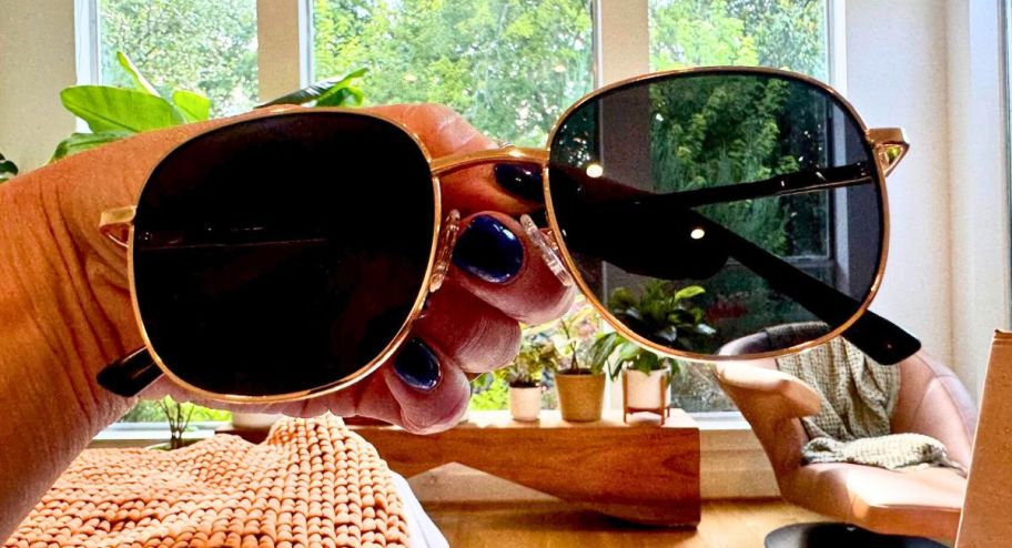 hand holding amazon sunnies inside of a bedroom