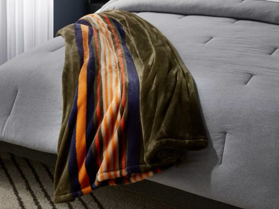 multicolored green stripe plush blanket on grey bed